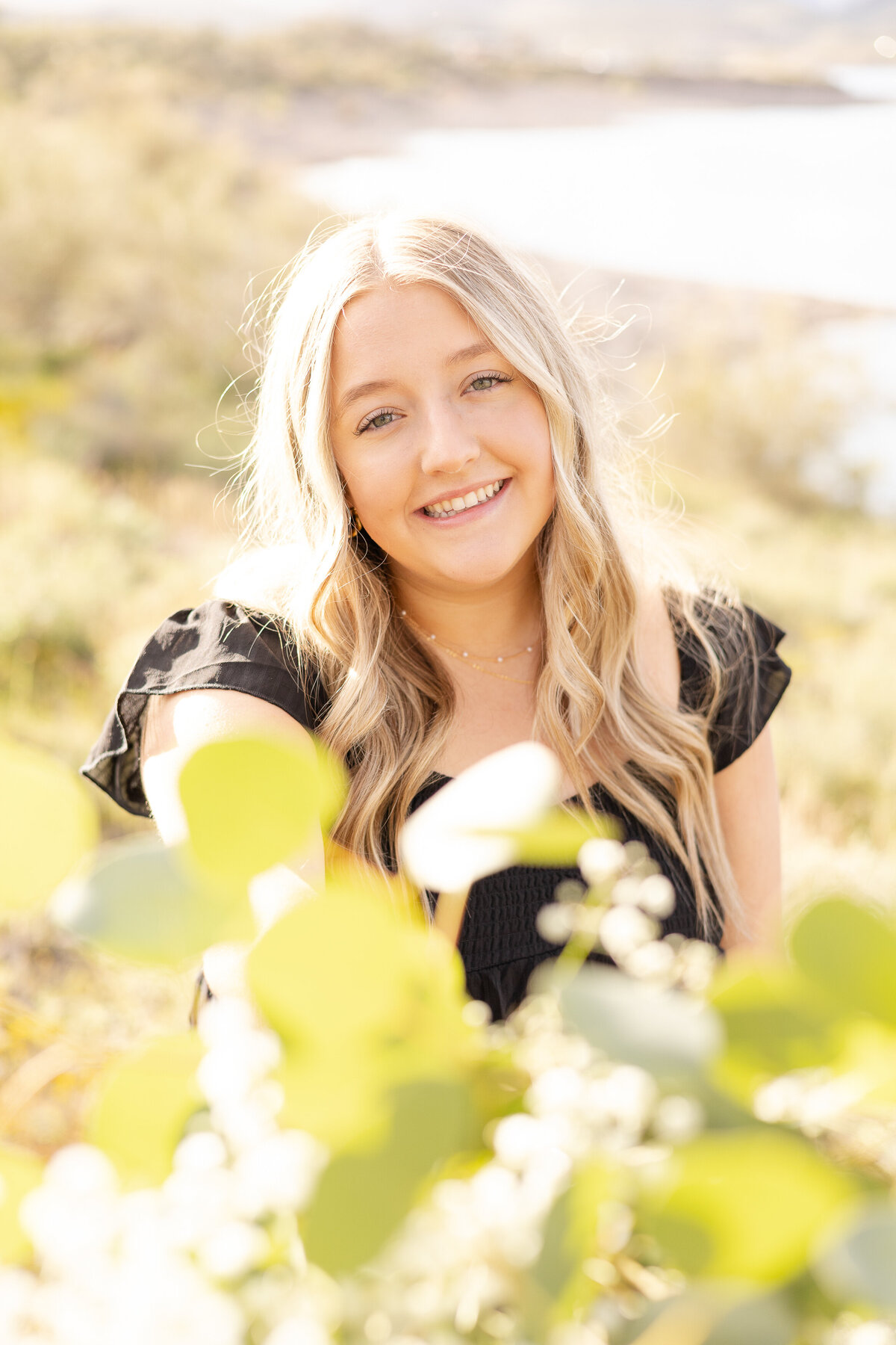 Senior holds eucalyptus bouquet during senior photography session at Lake Pleasant in Peoria, Arizona.