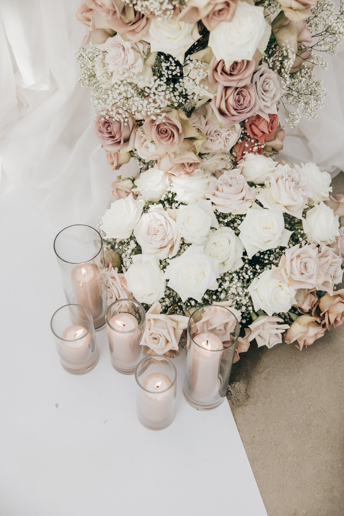 Detail shot of perfect pink and white roses, lavender candles, and baby's breath at luxurious wedding