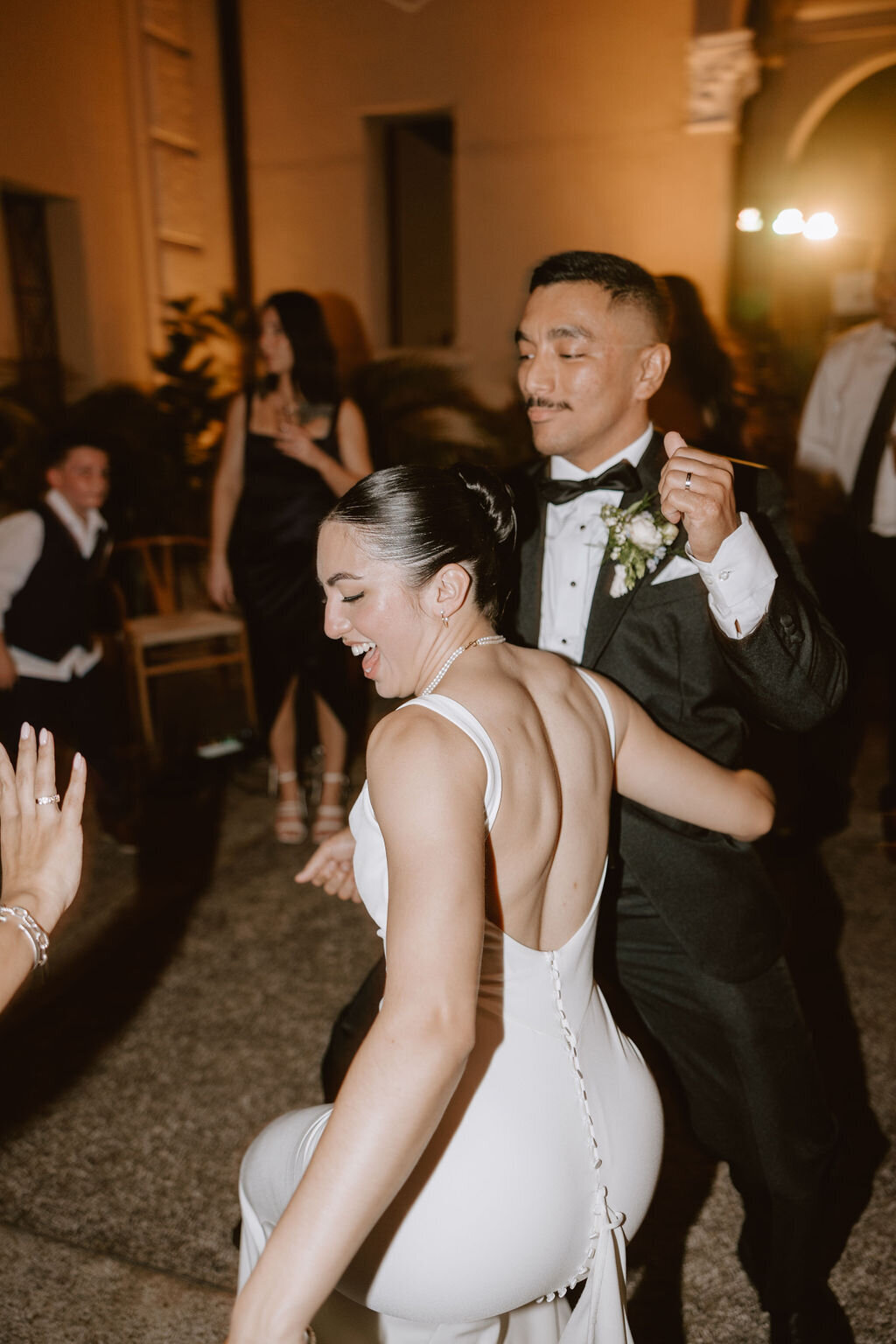Bride getting low while dancing and holding onto grooms waist
