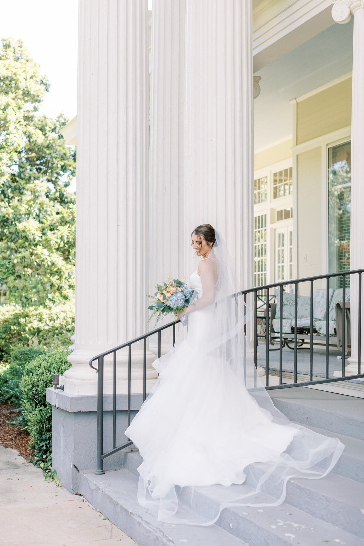 A bride stands by a white column.