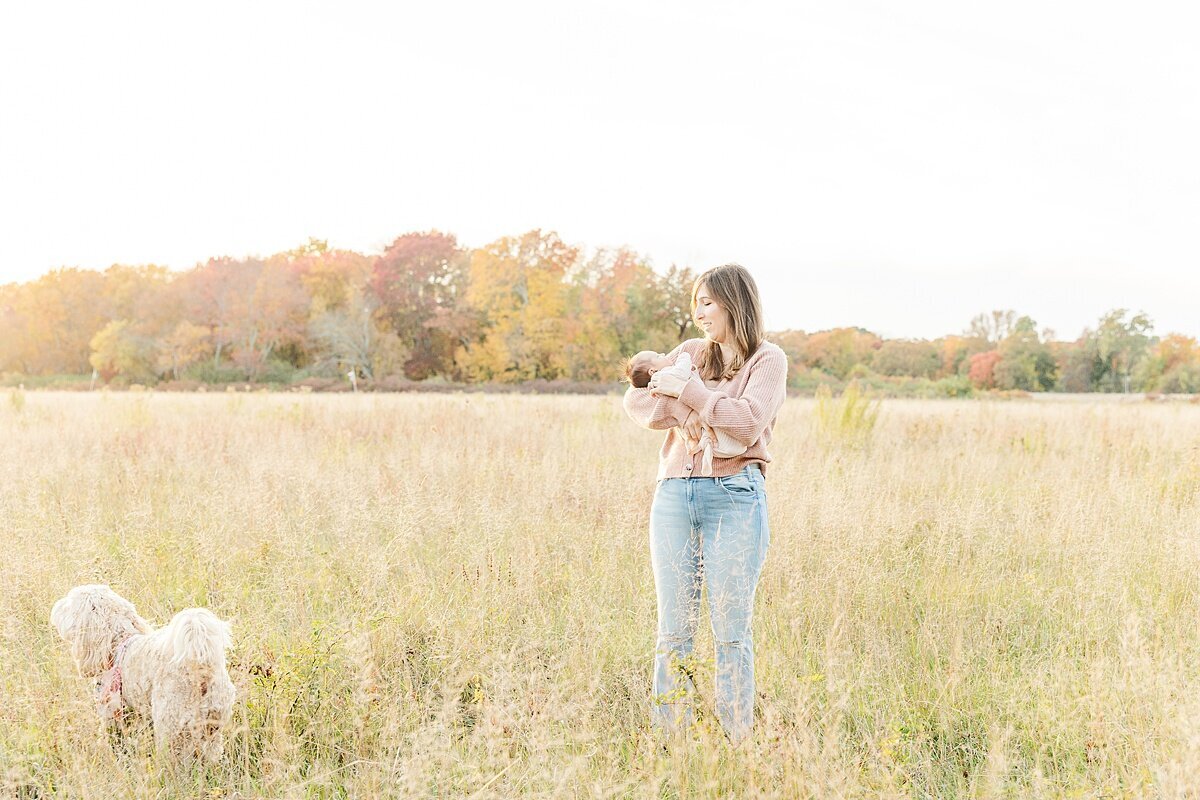 mom stands in field during outdoor newborn photo session with Sara Sniderman Photography