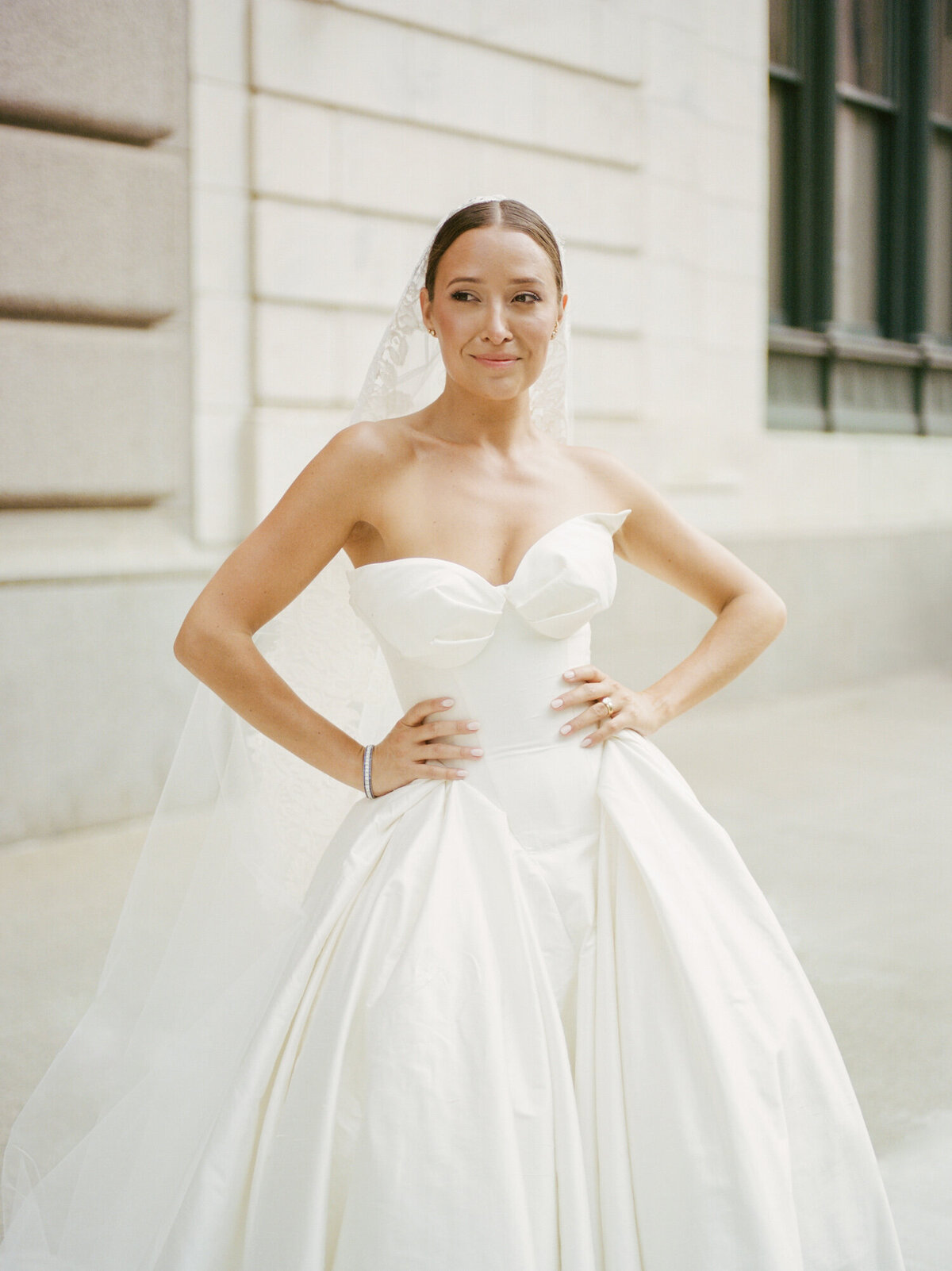 a bride poses confidently in her silk Leah Dagloria ballgown during her State Savings bank wedding in Detroit