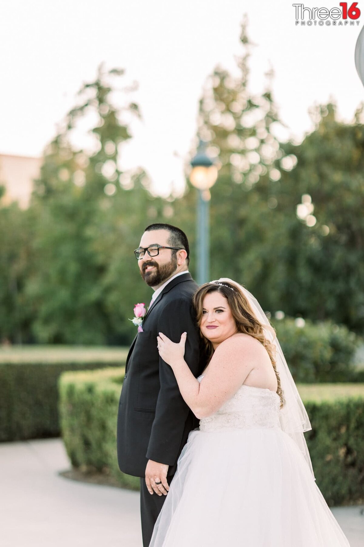 Bride embraces her Groom from behind during photo shoot
