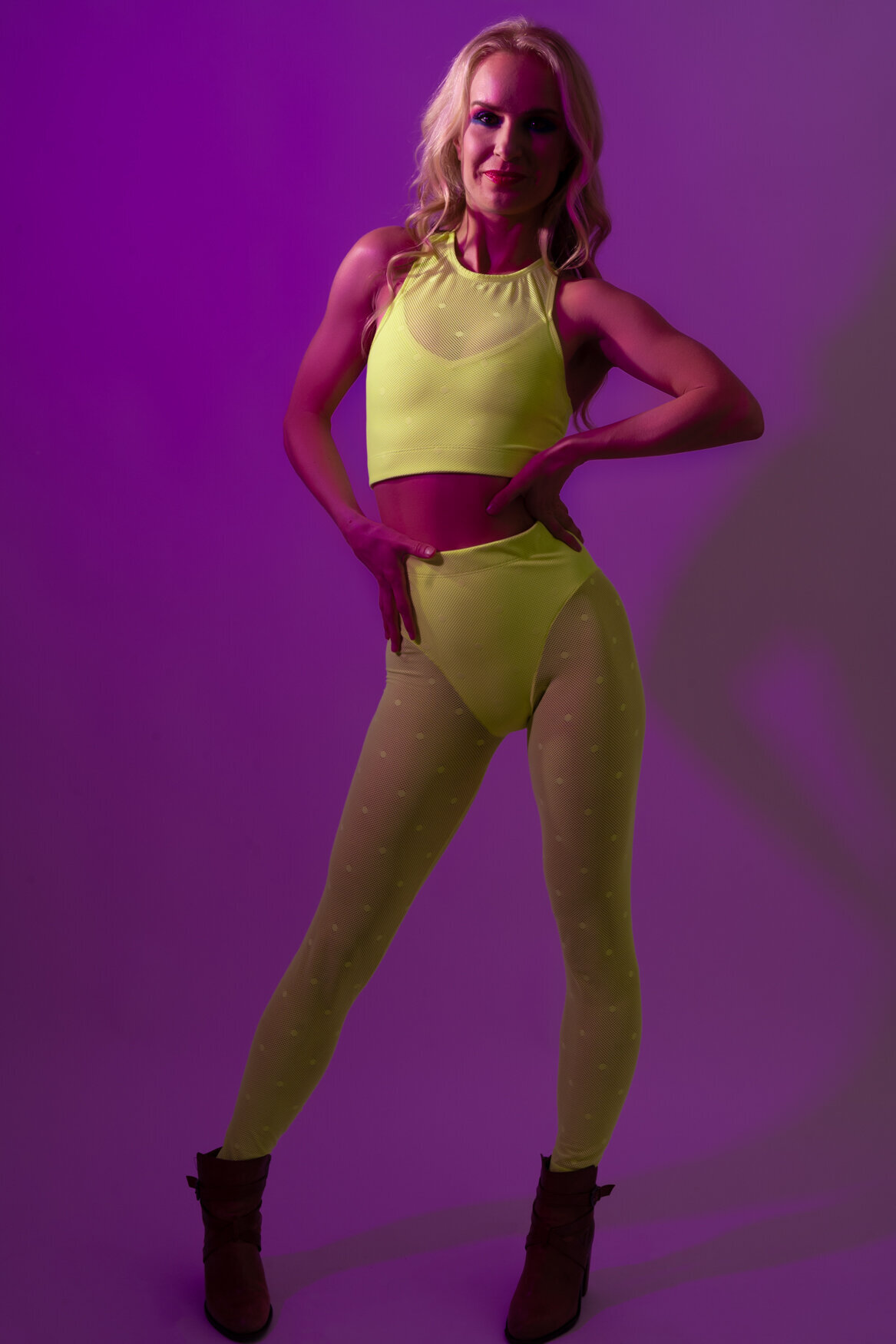 a portrait of a woman standing in front of the camera with her hands on her waist smiling wearing neon clothes
