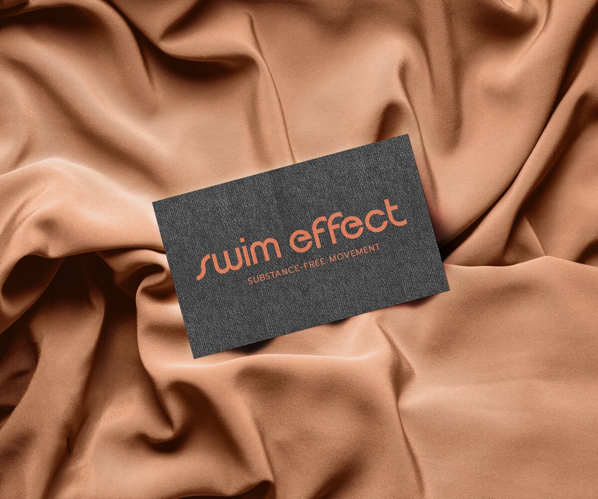 A card with the text "swim effect: SUBSTANCE-FREE MOVEMENT" lies on a draped brown fabric, embodying refined brand strategy services.