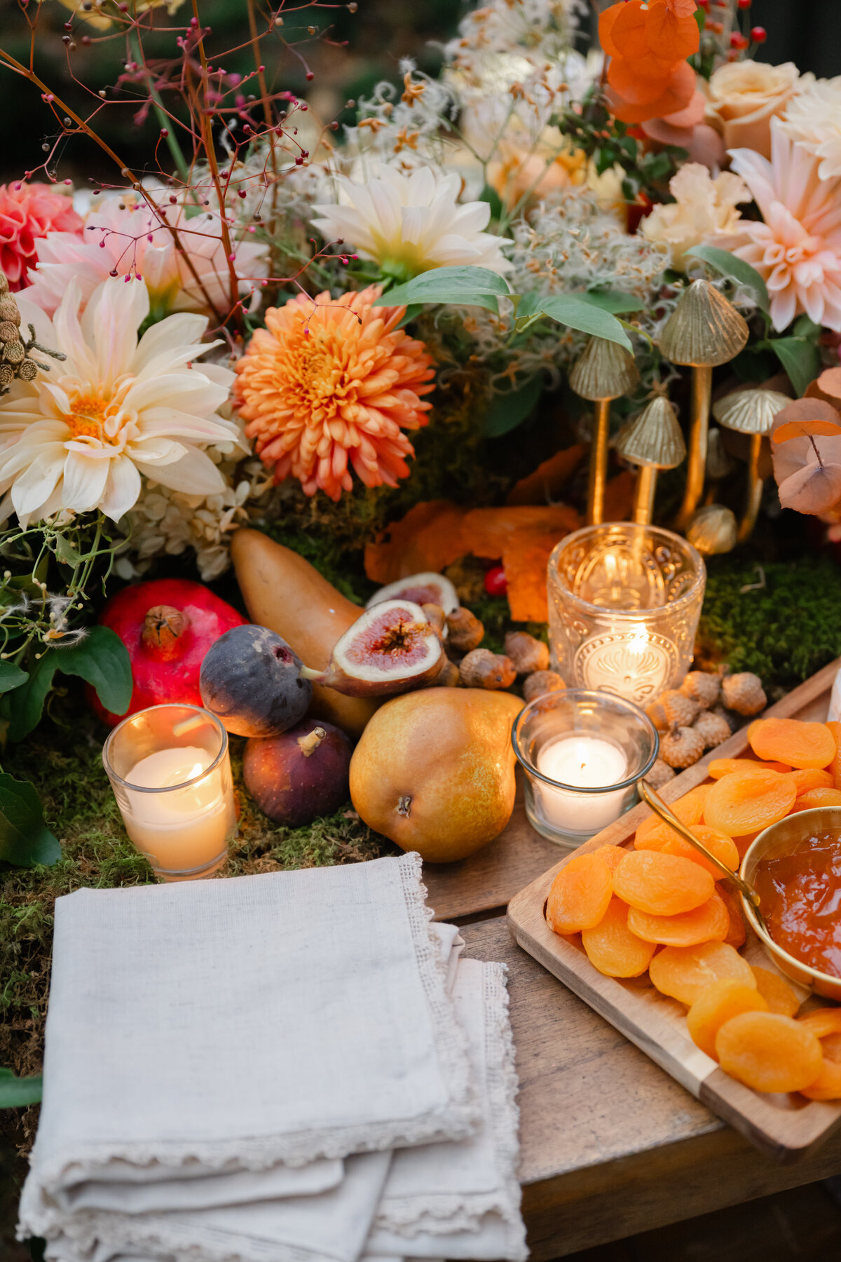 Close up of fruit surrounded by candles and flower arrangement
