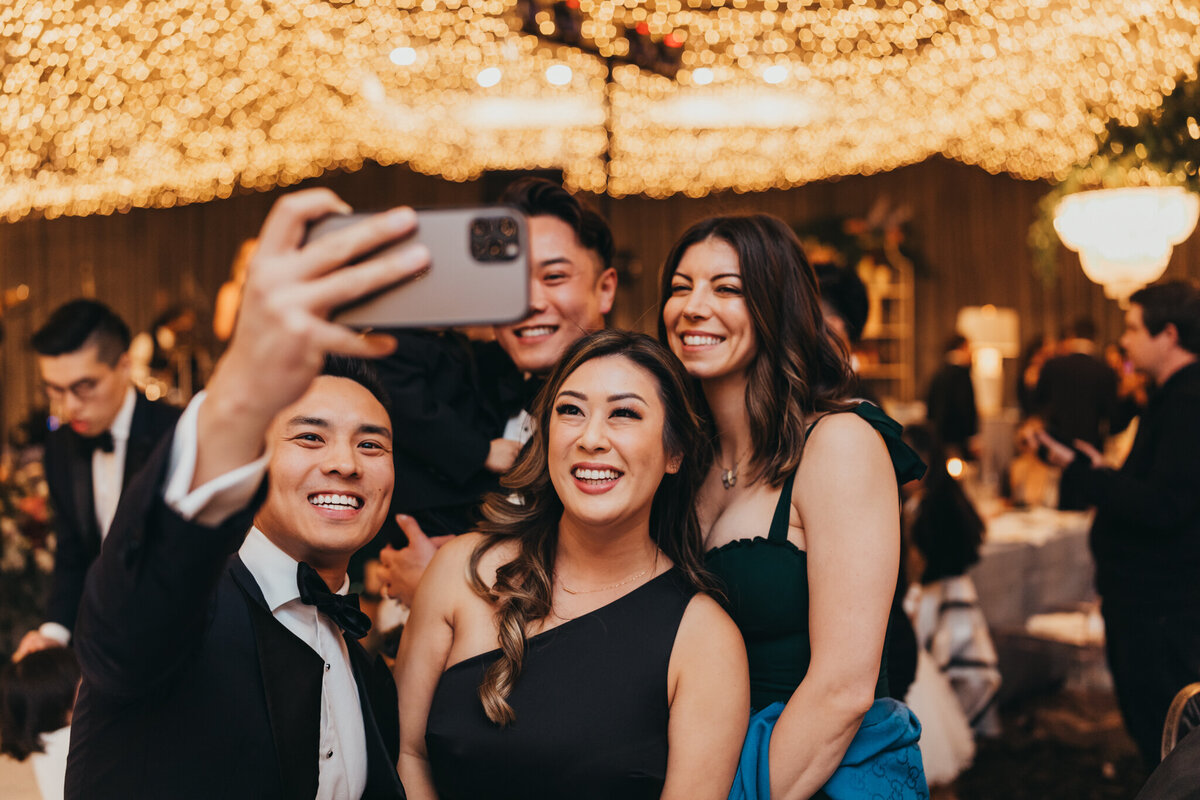 friends and family take a selfie duirng wedding reception