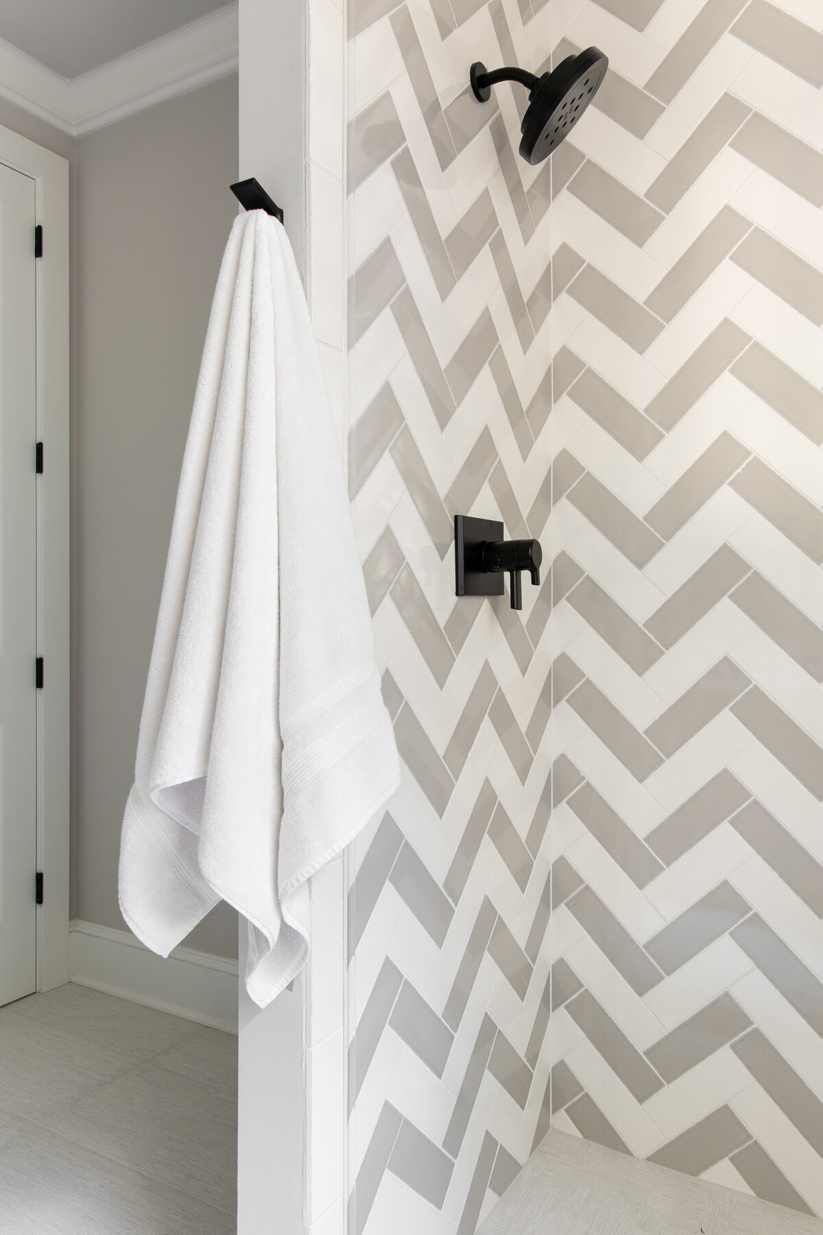 Modern bathroom in Kiawah Island, SC, featuring a sleek chevron tile shower with black fixtures.