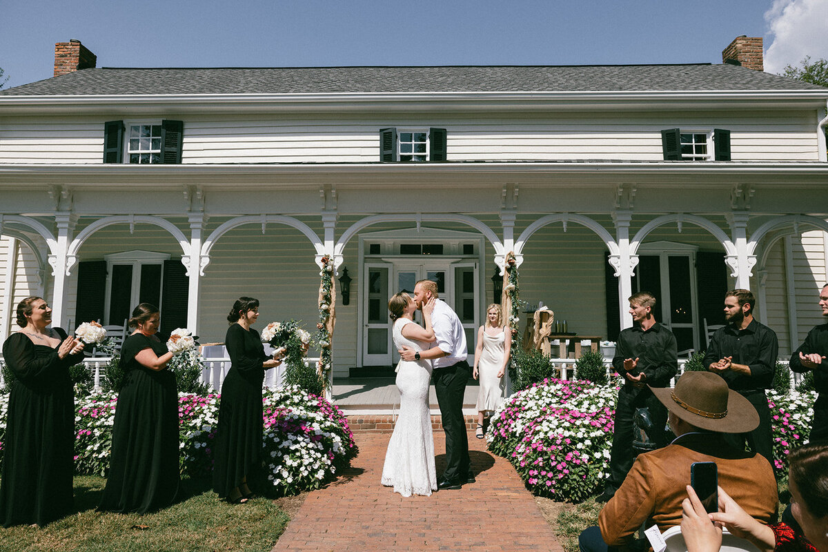 Bride and groom share first kiss in front of a historic home at their intimate wedding in Tennessee.