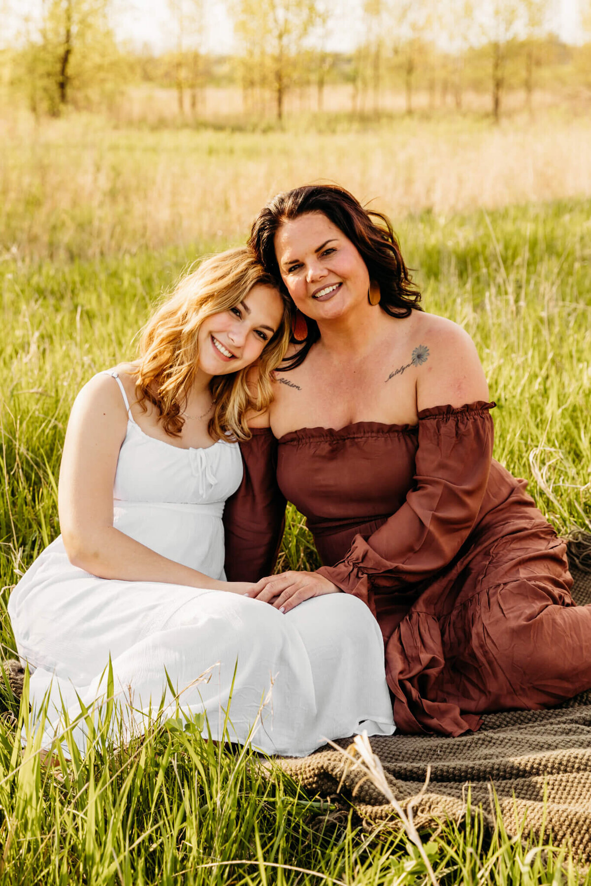 beautiful mother and her daughter snuggled up in a field for family photo session
