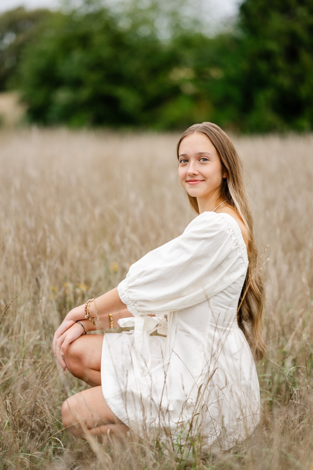seattle high school senior in white dress at discovery park open field