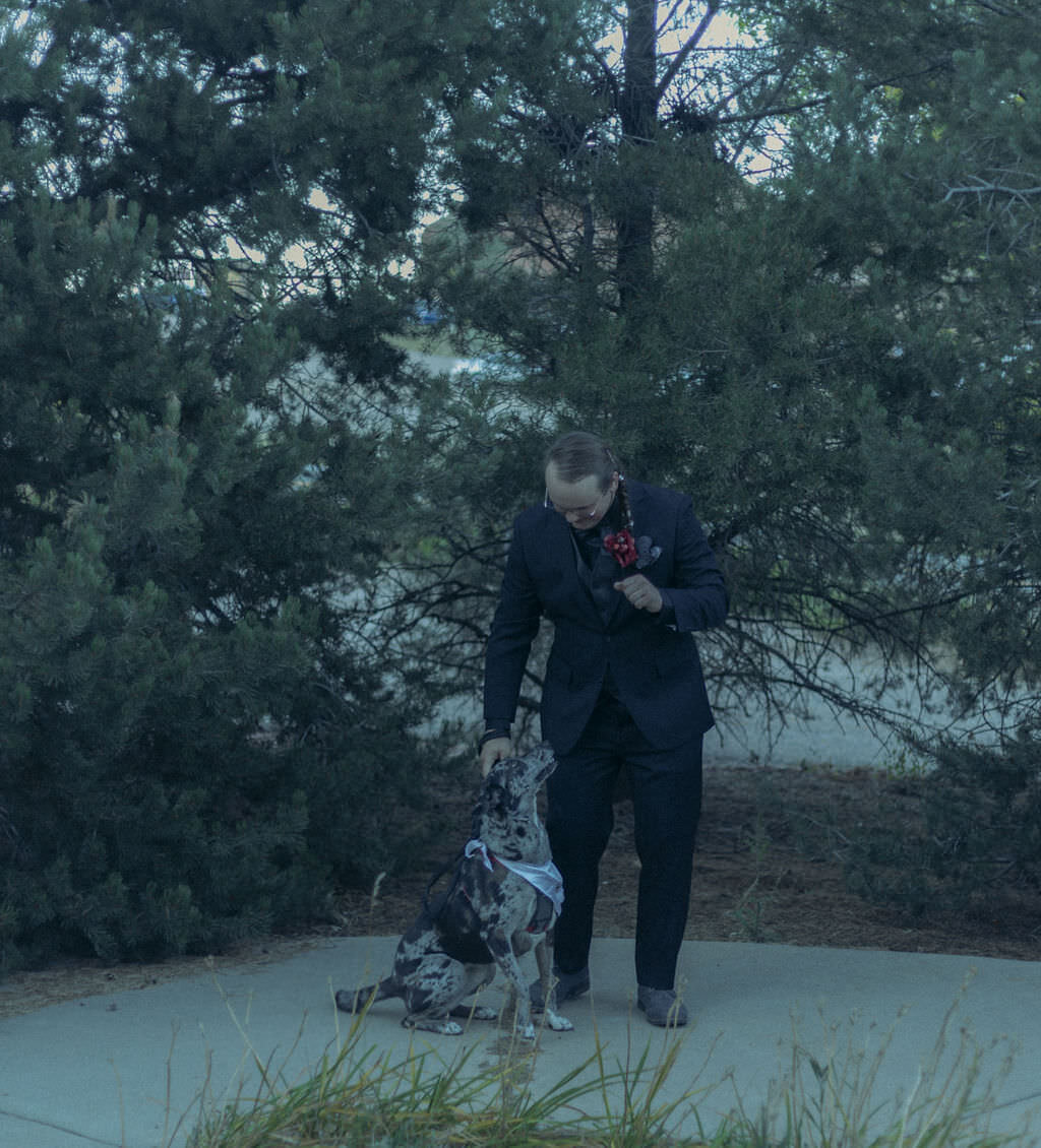 A person in a suit petting a dog.