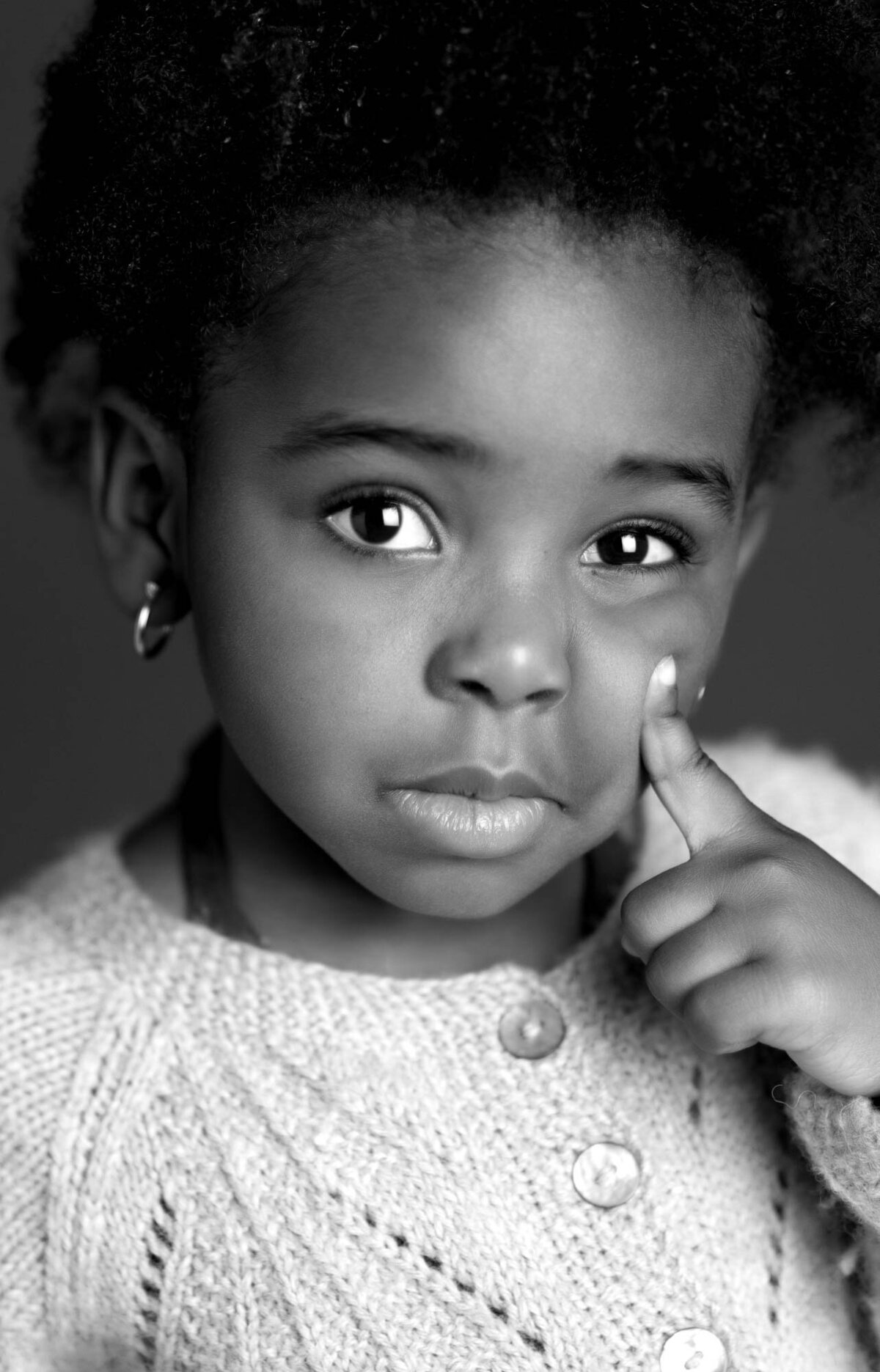 A black and white photo of a young girl smiling, with soft lighting highlighting her features.