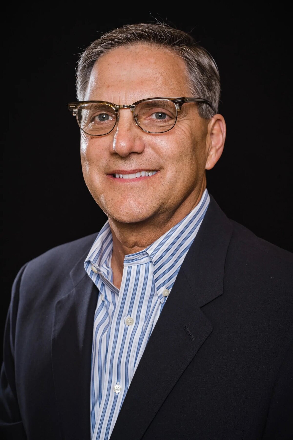 A man in a suit with glasses smiling