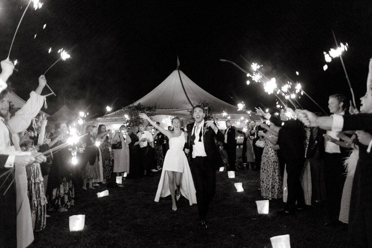 The bride and the groom happily came out of the tent wedding venue and met outside by guests holding sparklers at The Ausable Club, NY.