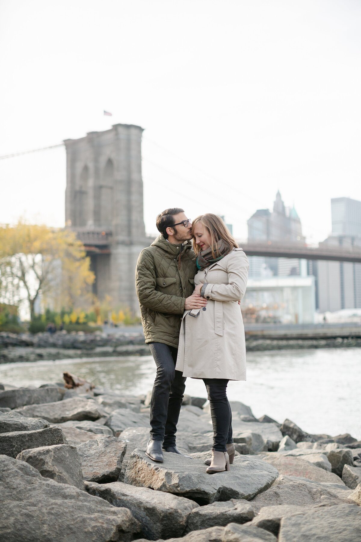 Pregnant couple pose near Brooklyn Bridge.