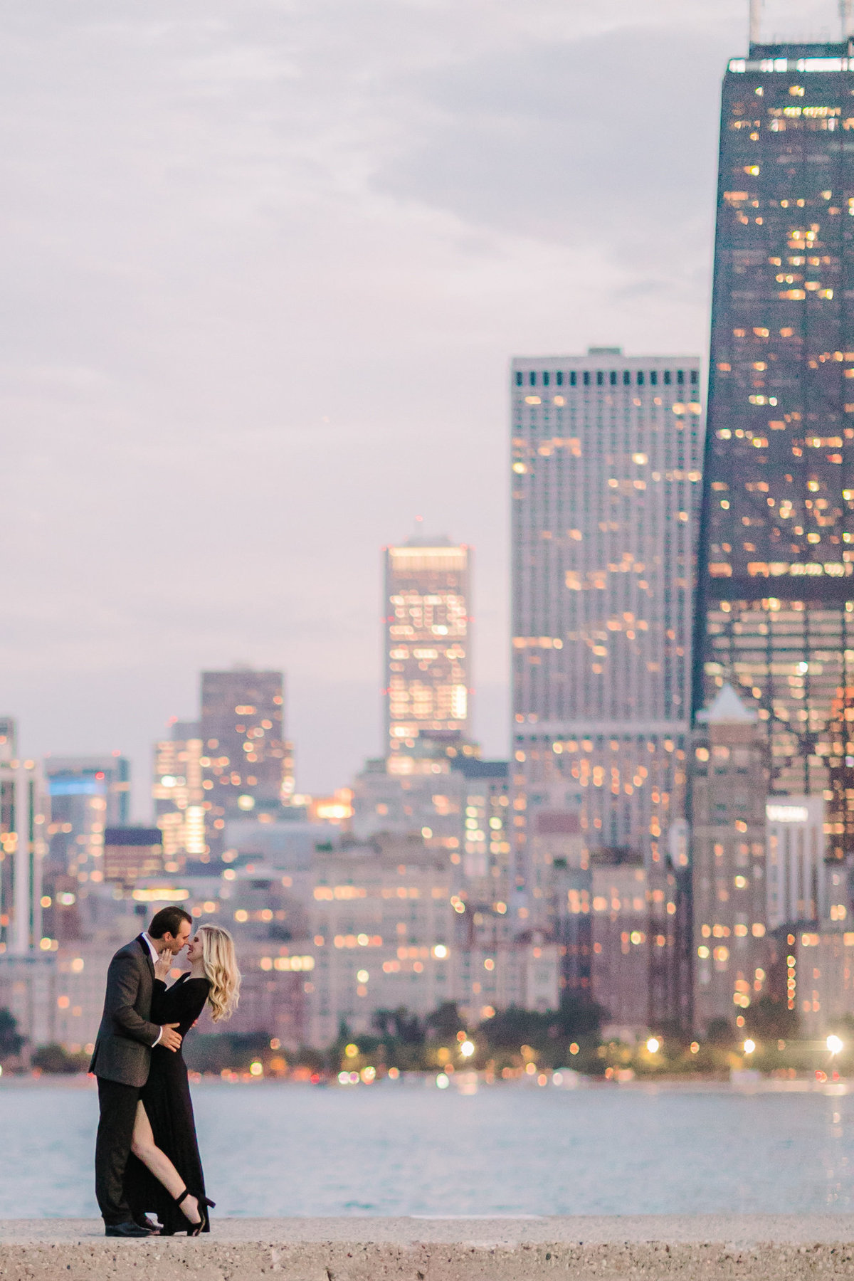 An engagement photo in front of the Chicago skyline as the lights glimmer in the background