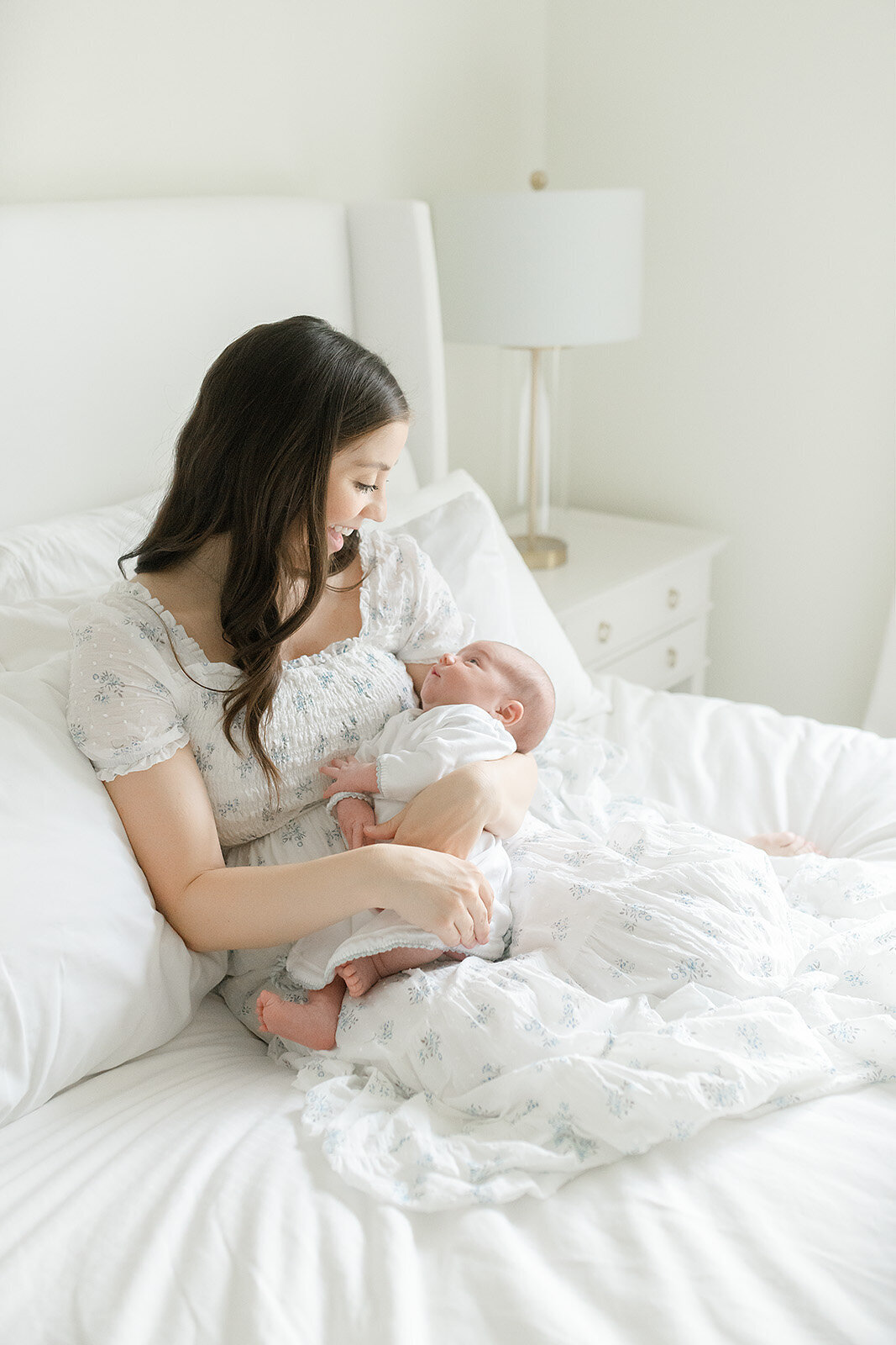 a mother connecting with her newborn on a bed in a white room