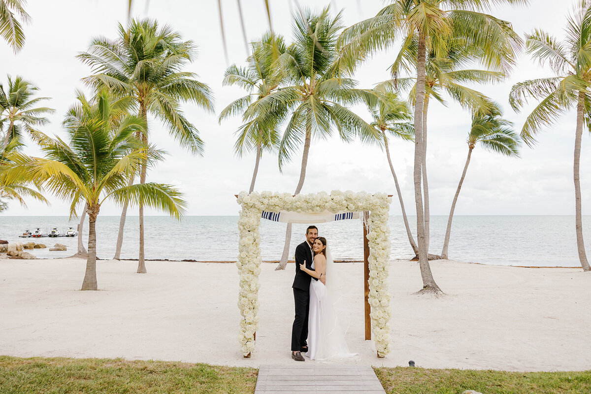 A romantic embrace as husband and wife at a stunning beachfront micro wedding in the Florida Keys. Destination wedding photography by Claudia Amalia.