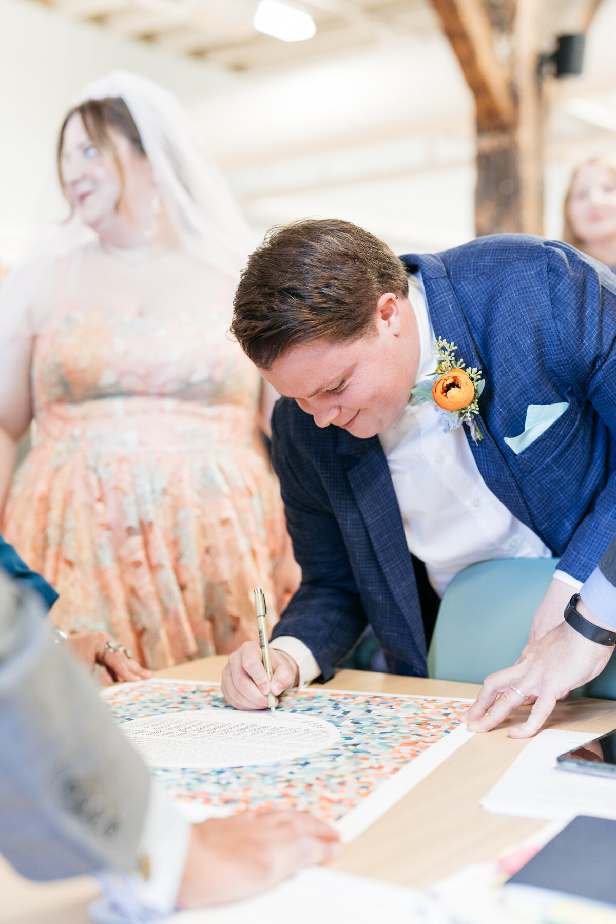 bride and groom signing colorful ketubah