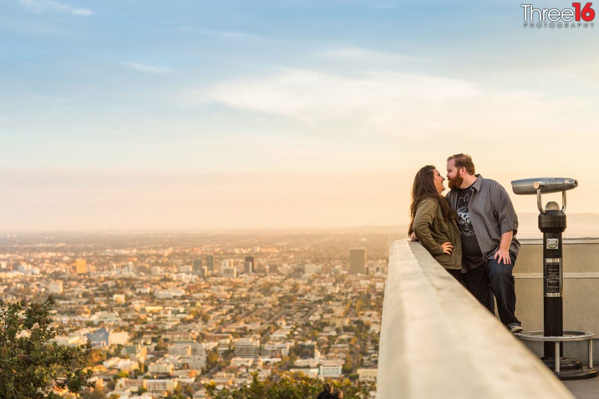 Engaged couple talk on the Griffith Observatory balcony overlooking LA