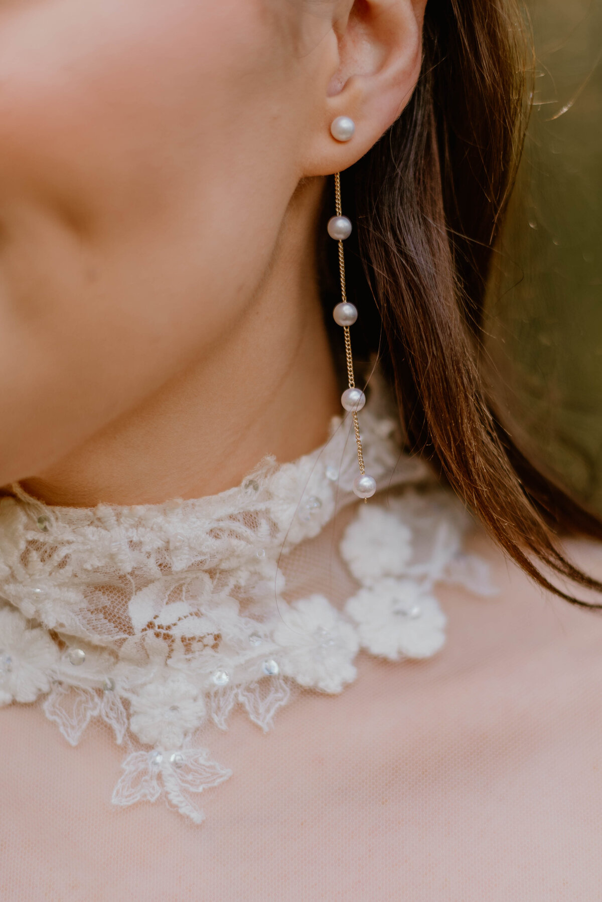 a detailed photo of a brides beaded wedding earrings also showing off her lace cuffed neckline of her wedding dress.