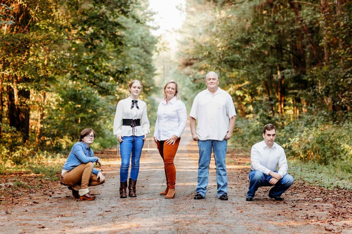 A group of 5 pose standing and squatting for their family portrait.