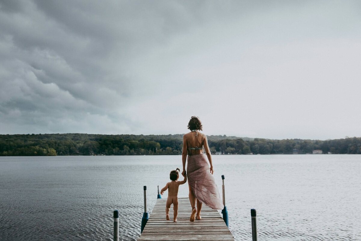 family portrait of a mom walking with her daughter on a stormy lake