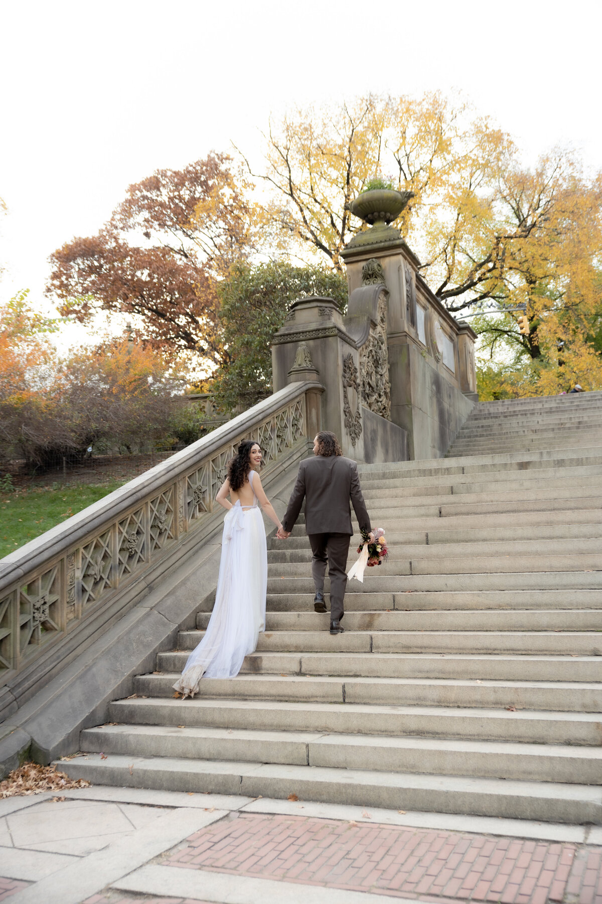 Bride and groom sharing a quiet moment under golden fall trees in Central Park.