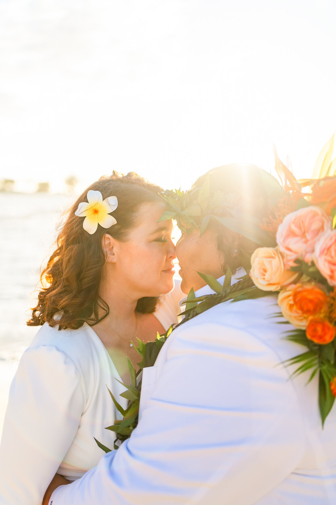 brides holdign eachother eyes closed on the beach at sunset