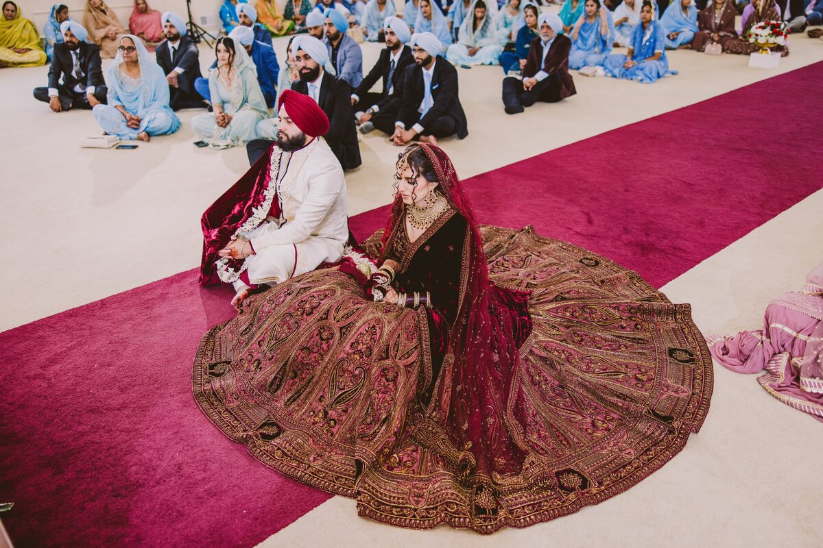 a sikh bride and groom sitting during their anand karaj wedding ceremony at the bridgewater gurudwara nj