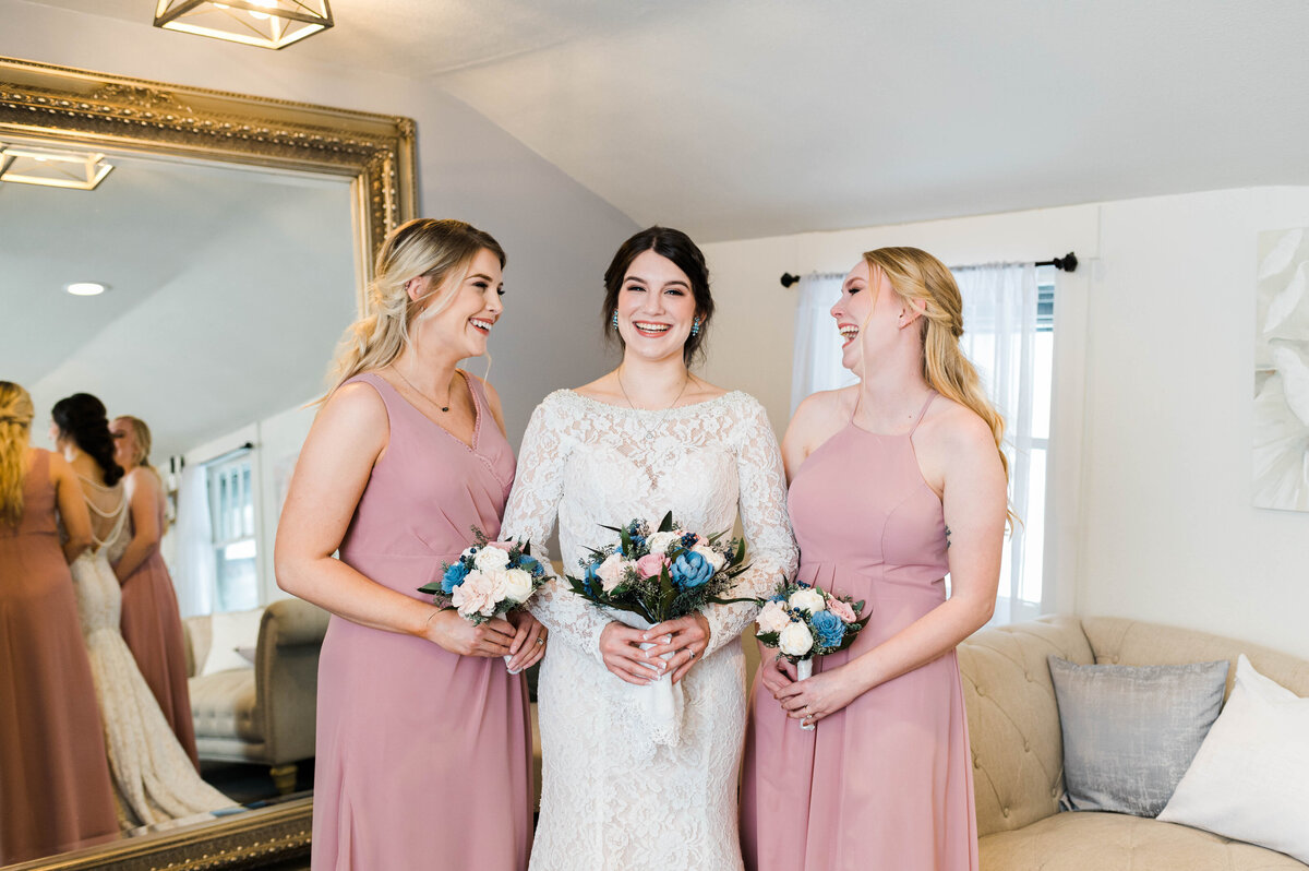 A bride smiles with her bridesmaids in the bridal suite as the bridesmaids smile at her at Boulder Wedgewood Venue