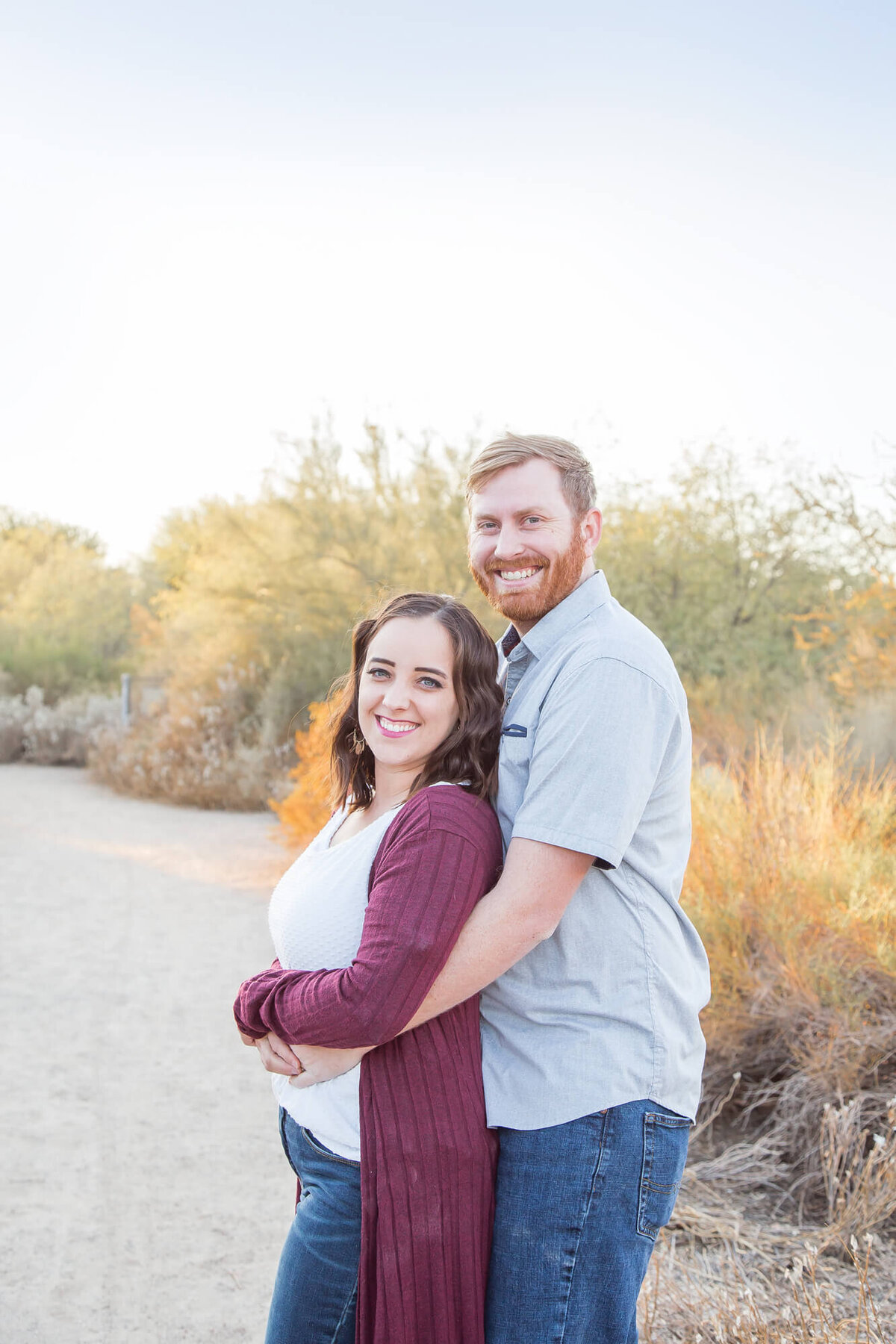 redhaired Man hugging woman from behind on a desrt path