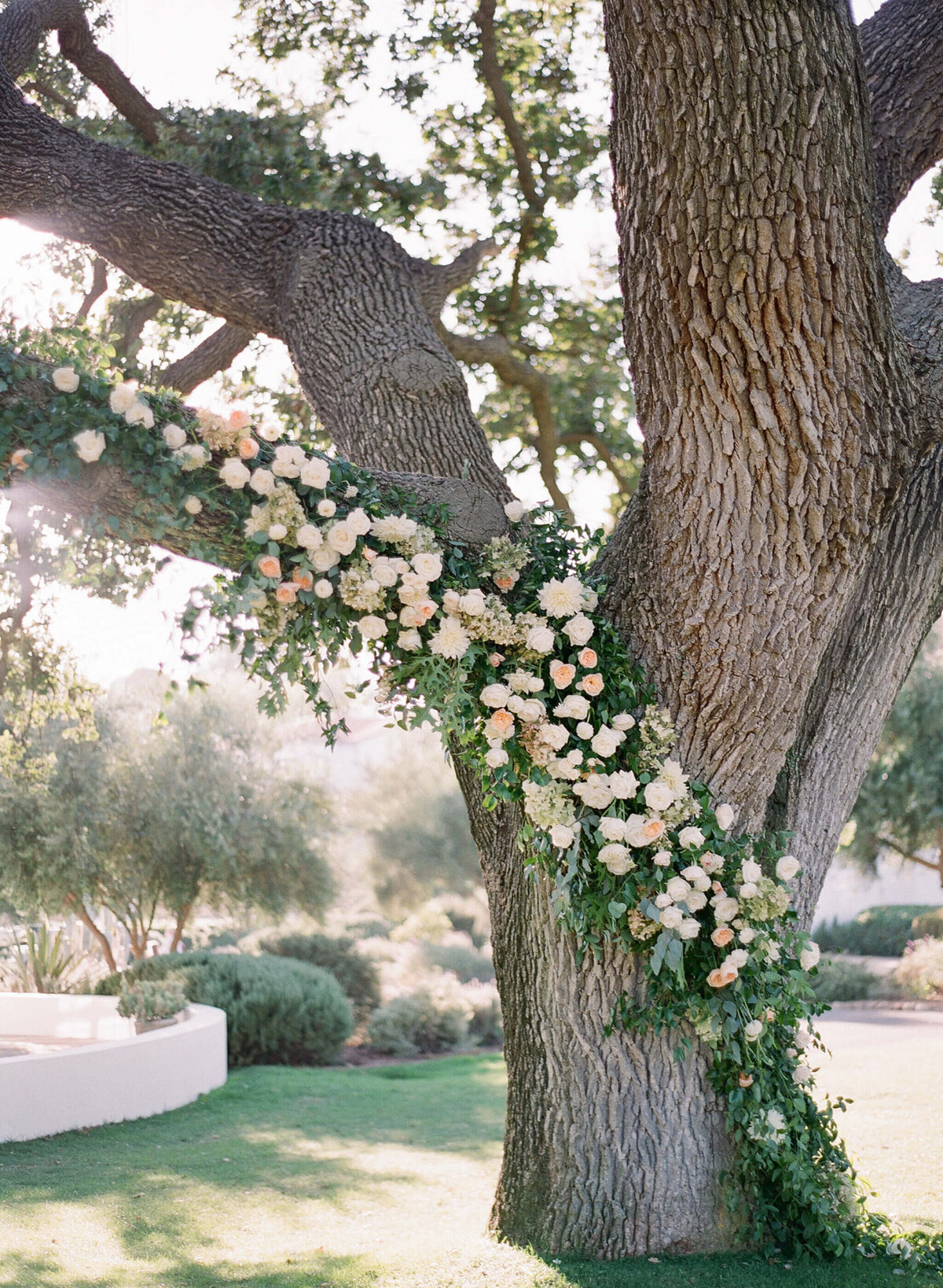 Custom tree garland decor floral arrangements at a bespoke outdoor wedding