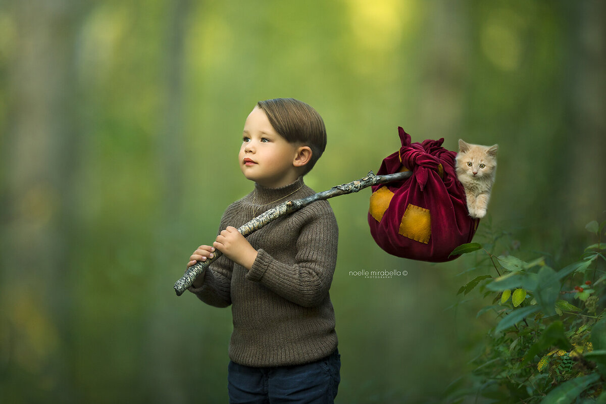 Boy in the forest holding hobo sack with kitten in it.