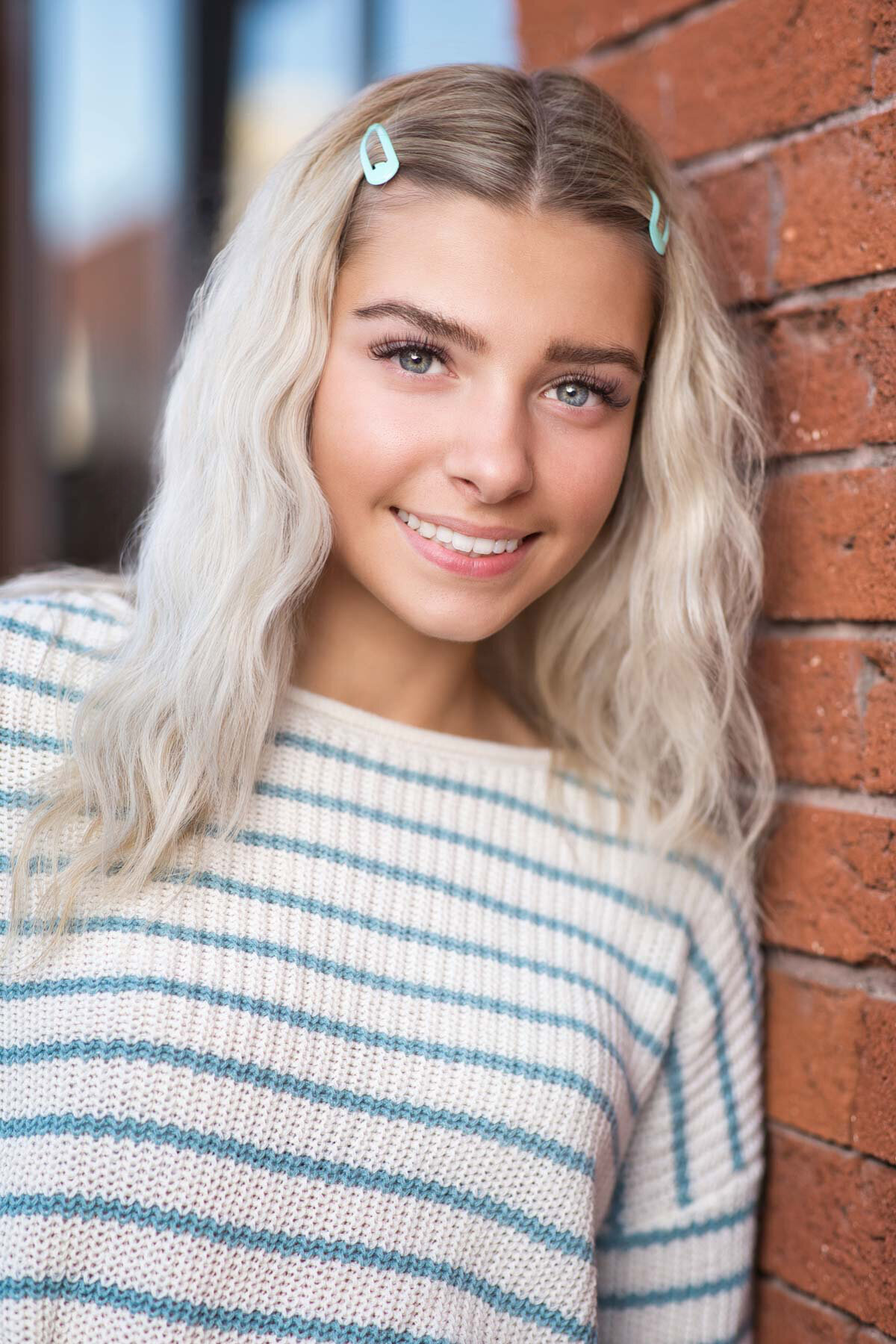 Utah senior girl posing against a red brick wall in Salt Lake City Utah.