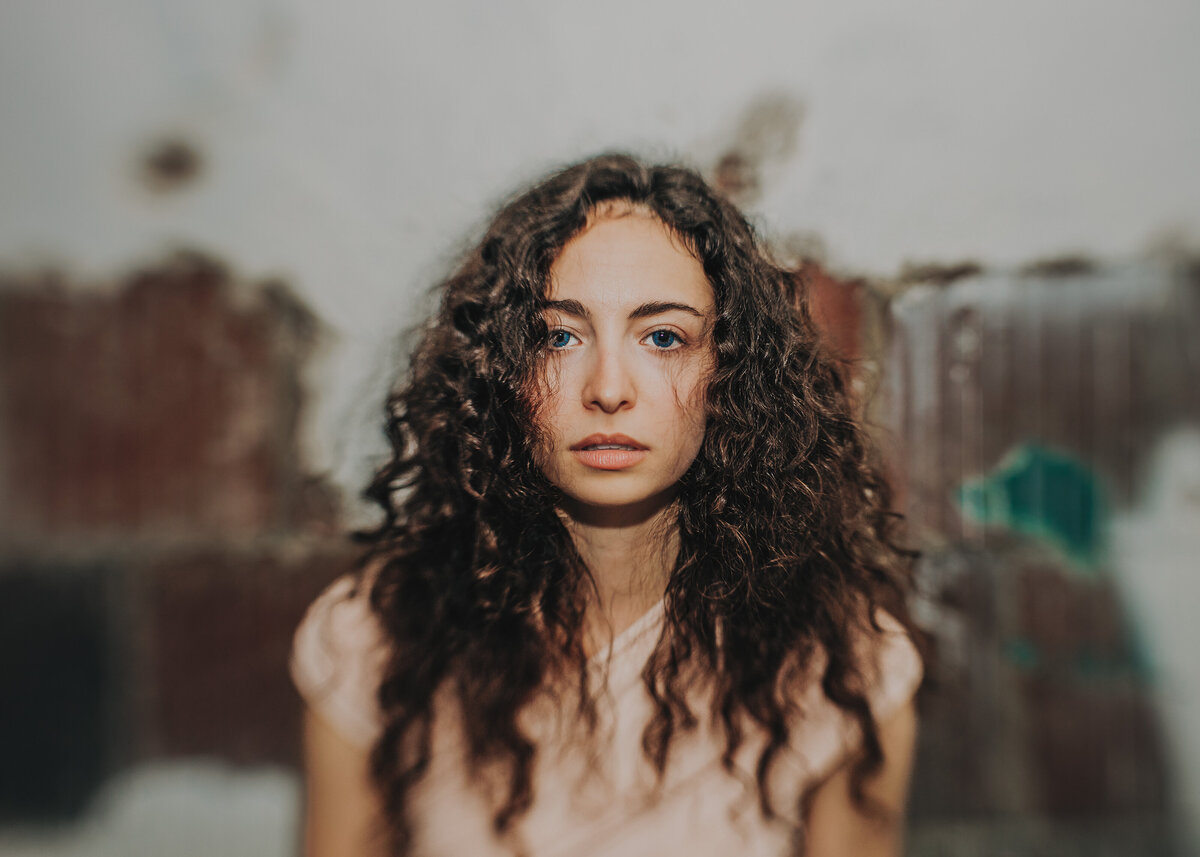 Close up of woman with messy hair with brick wall in the back and blur effect