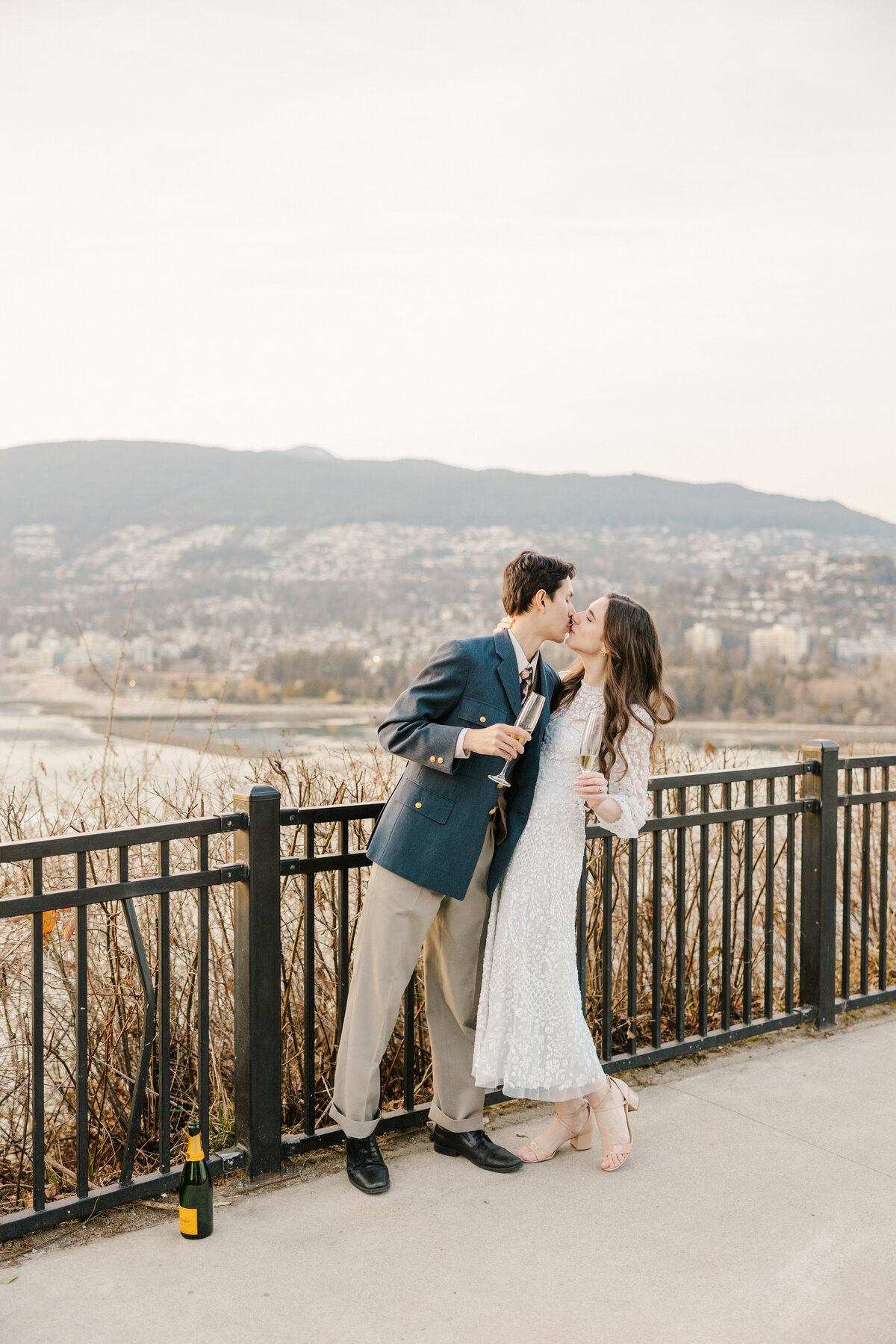 Couple kissing in front of a mountain landscape holding champagne flutes