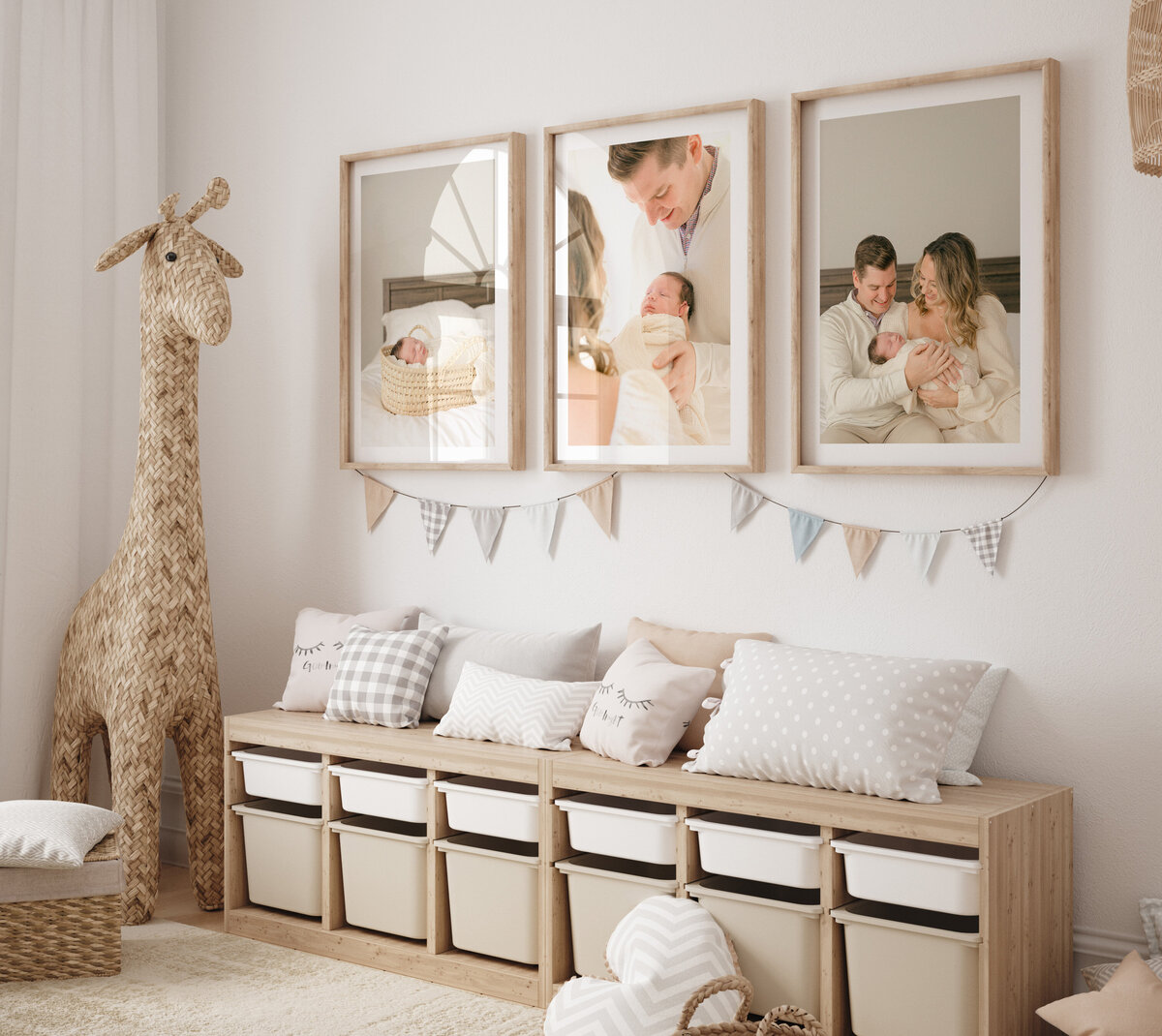 A toddler's giraffe themed playroom features framed Indianapolis newborn pictures hanging over a toy storage bench.
