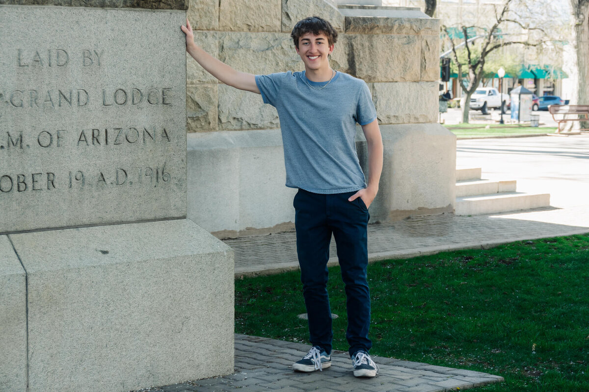 Young man poses at Yavapai County Courthouse in Prescott senior photography session