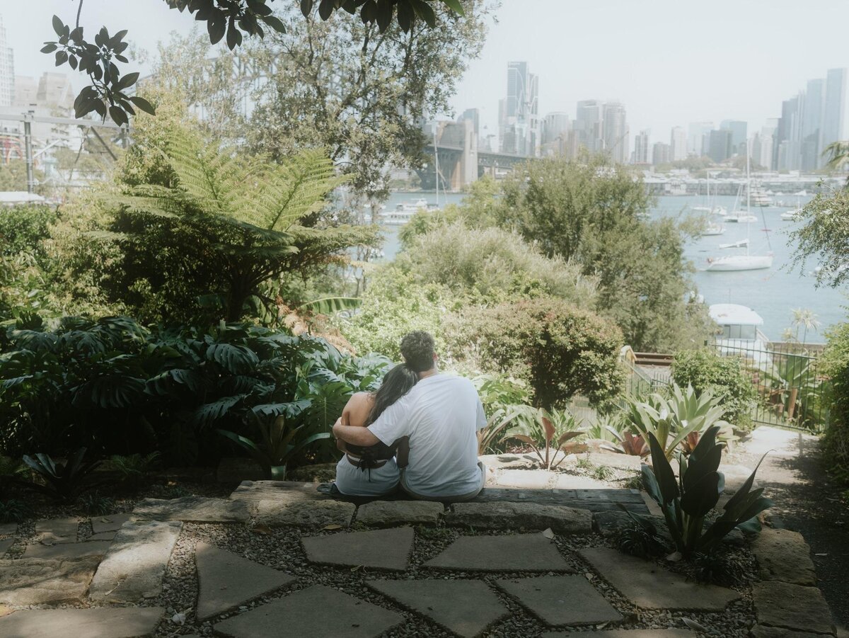 Couple sitting together at Wendy’s Secret Garden with a stunning Sydney Harbour and bridge view in the background