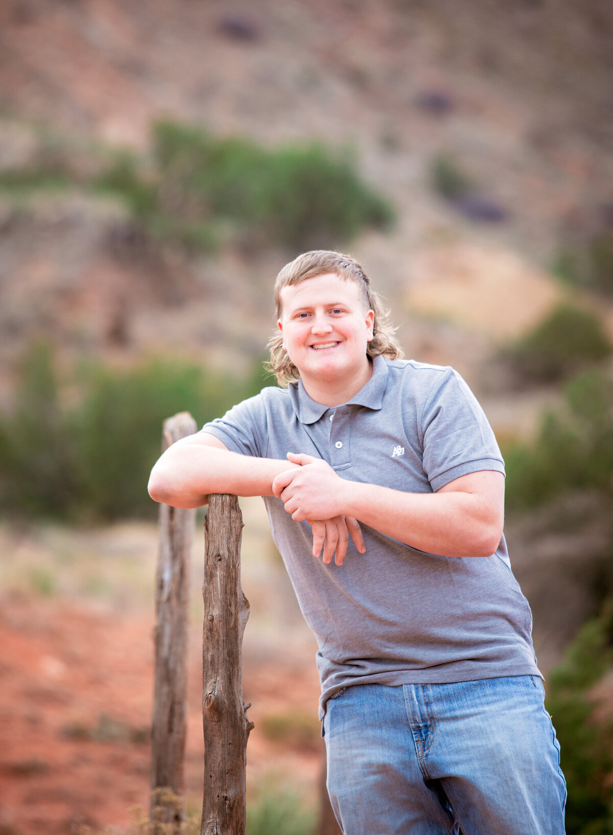 Senior boy leaning against fence in Palo Duro State Park Tx