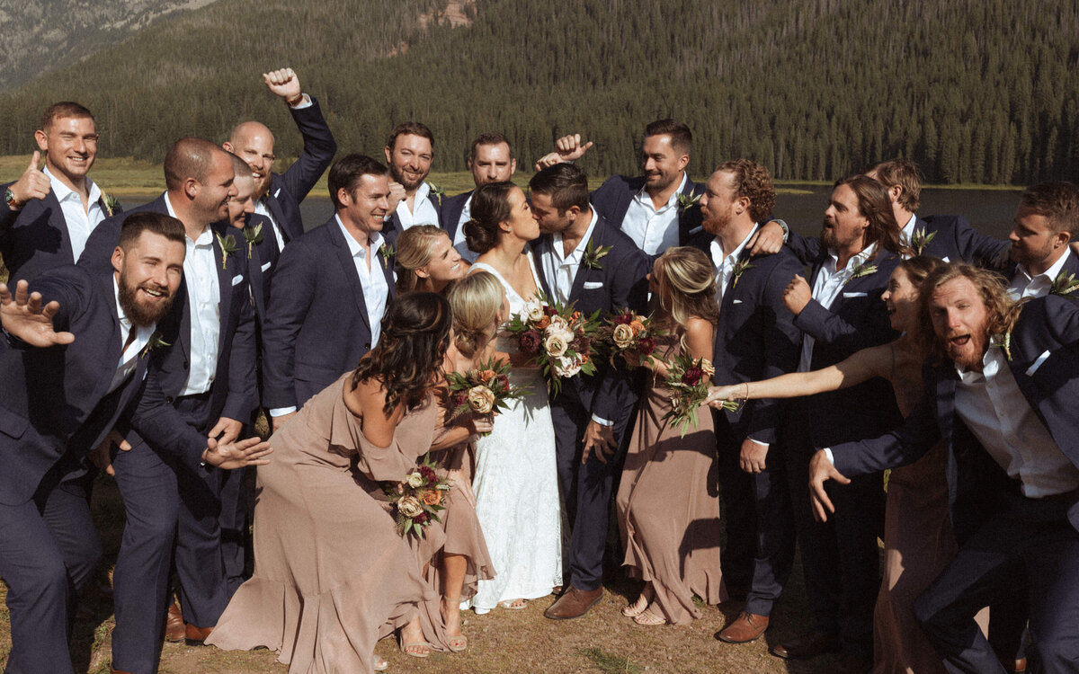 Bridal party celebrates with the bride and groom in mauve dresses and navy suits.