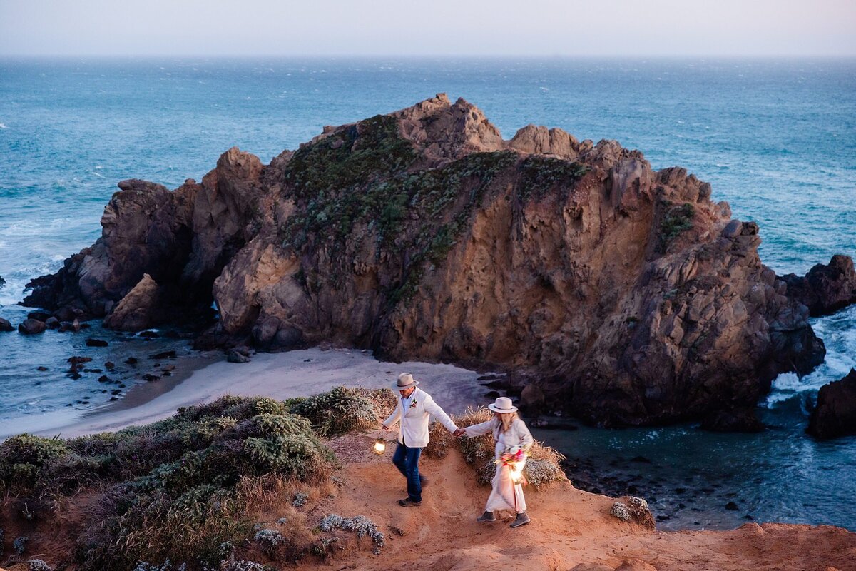 The bride and groom walk along the cliff edge at Pheiffer Beach in Big Sur. 