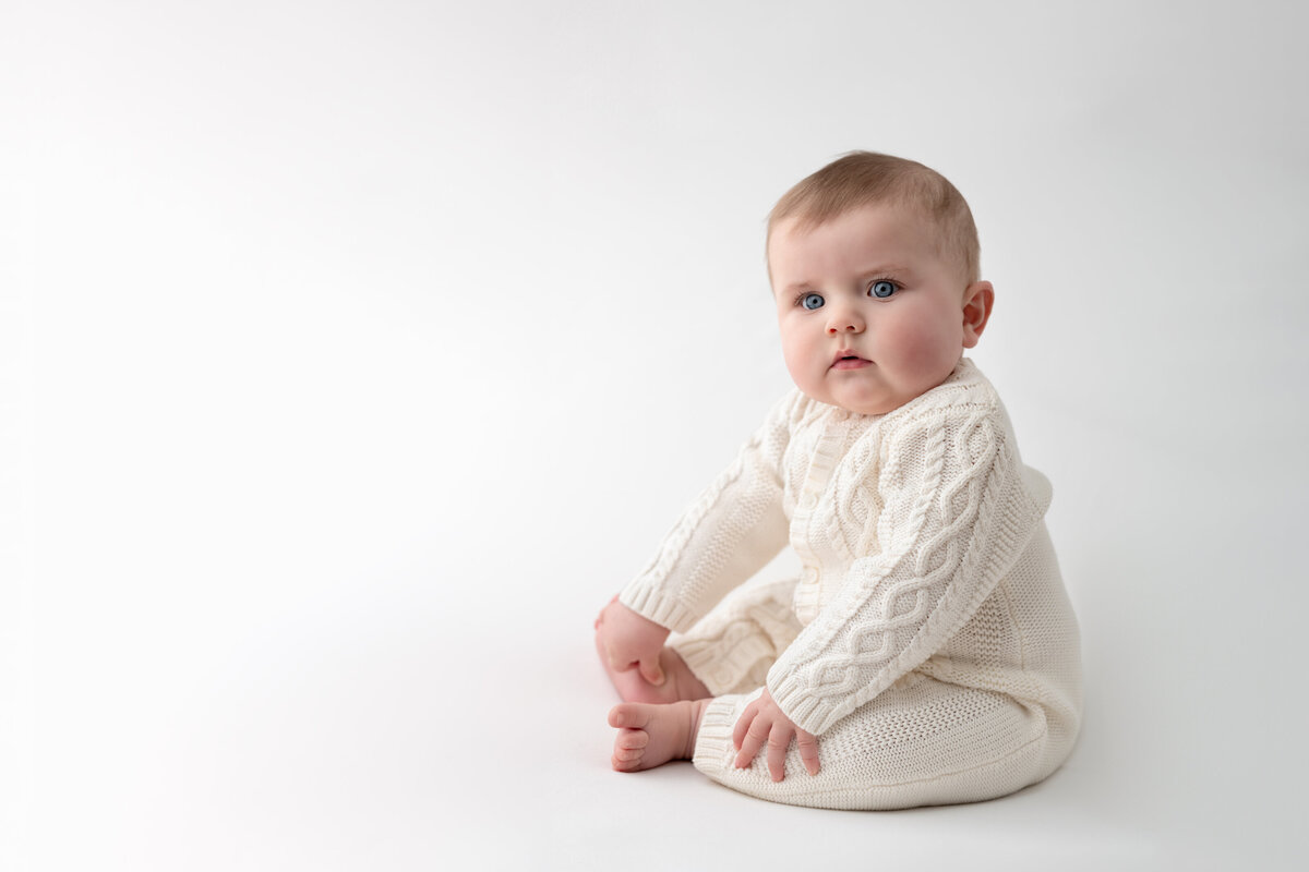 Classic sitter milestone portrait of a baby in cable knit cream—clean, pure, and beautifully timeless.