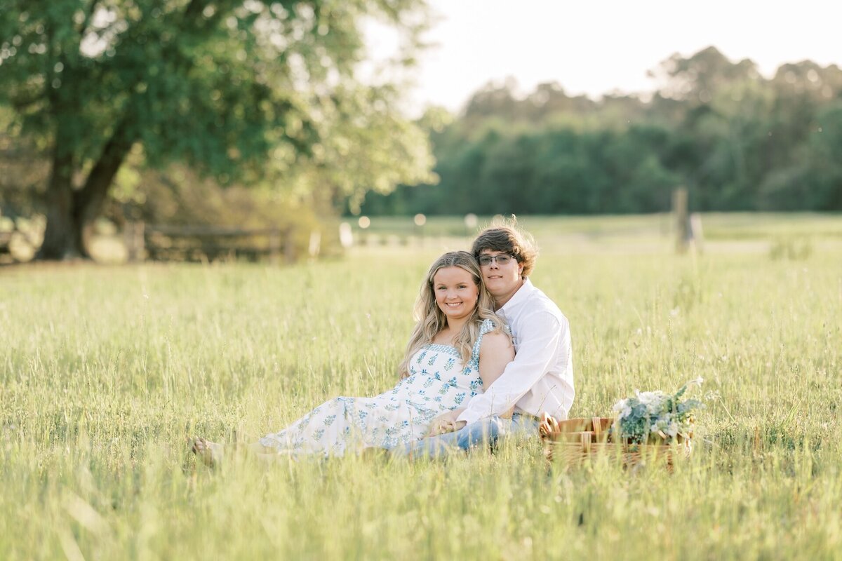engaged couple sitting in a field