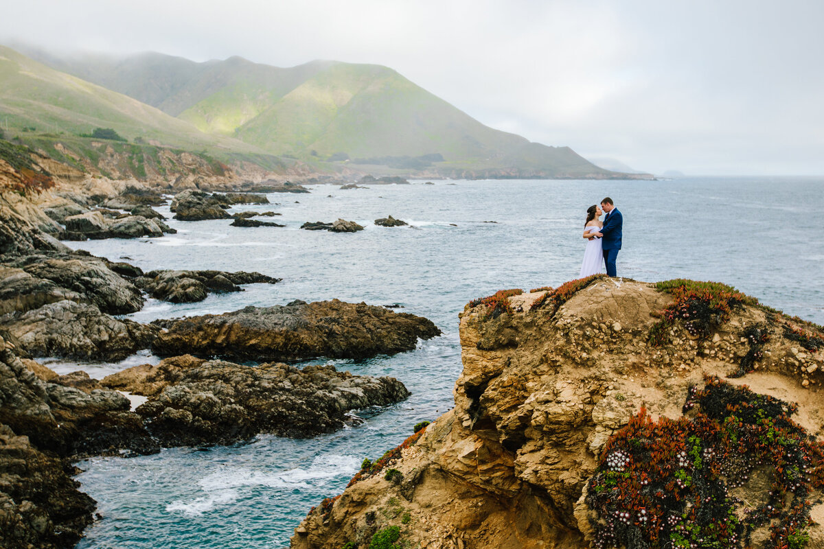 couple on cliff in front of water