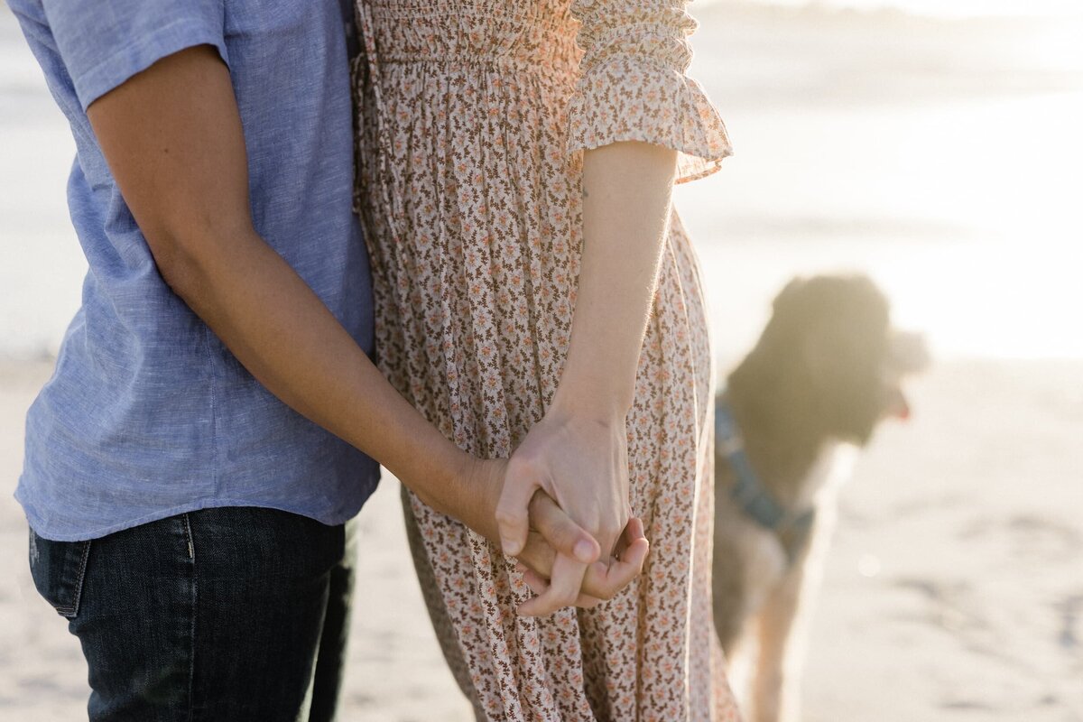 two girls holding hands on the beach at sunset