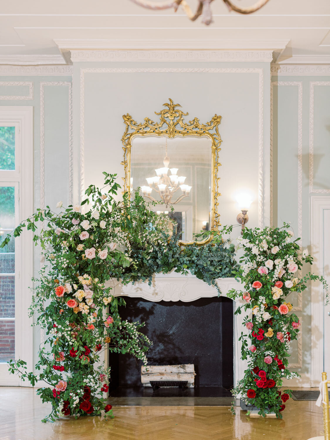 Floral ceremony arch over fireplace with gold mirror