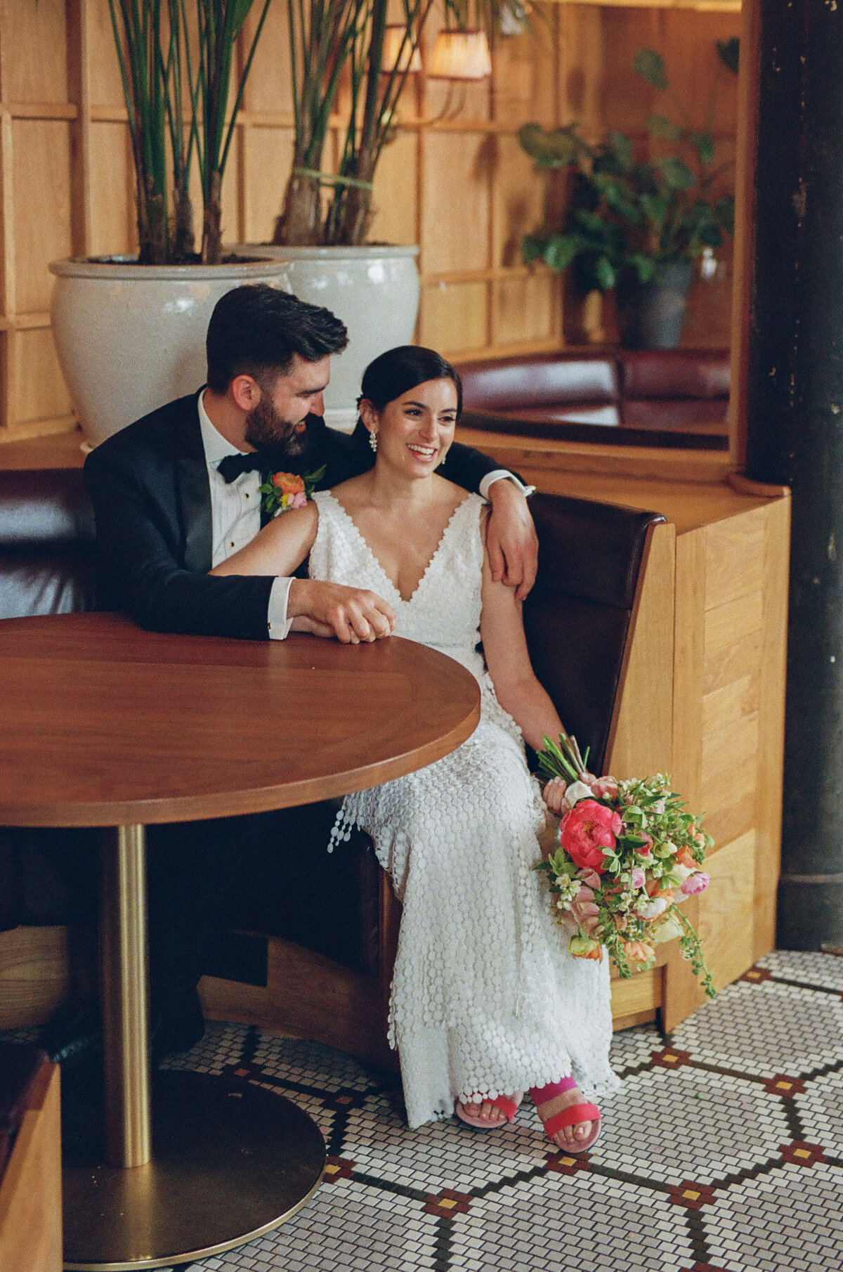 A bride and groom sitting in a booth together.